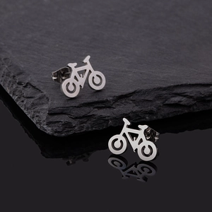 Macro shot of bicycle shaped stud earrings on black stone and reflective background