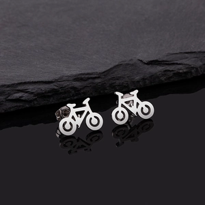 Macro detail of silver bicycle earrings on dark stone background with sharp metal highlights