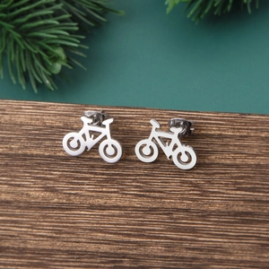 Close-up of minimalist silver bicycle stud earrings on a wood block with pine needles