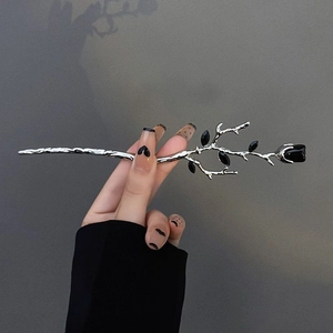 Detail of silver branch hairpin with black rose bud and leaves in gothic minimalist style