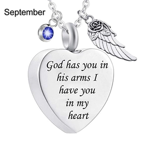 Macro detail of heart pendant with wing charm, blue birthstone, and engraved memorial text