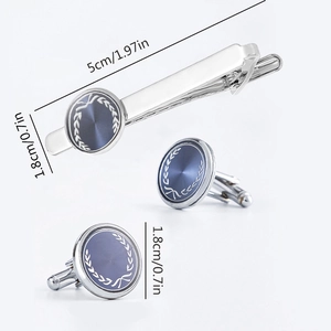 Silver cufflinks and tie clip set with blue laurel wreath pattern on white background