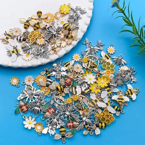 Detalle de dijes de abeja y margarita de aleación para joyería DIY en un plato decorado