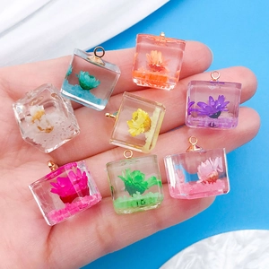 Close-up of cube resin charms with colorful dried flowers and golden metal loops