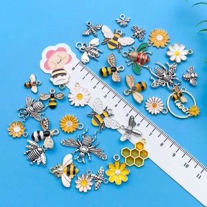 Detalle de colgantes de abeja y margarita de aleación con esmalte y pedrería fina