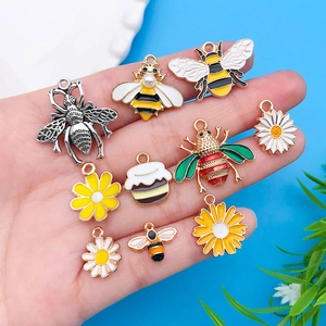 Detalle macro de dijes de abeja y margarita de esmalte para la creación de joyería DIY