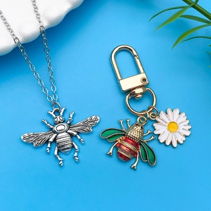 Detalle de los colgantes de abeja y margarita en aleación con esmalte de colores y metal