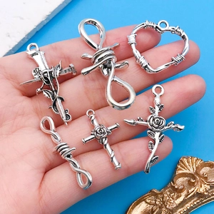 Gros plan de pendentifs croix rose et coeur en argent antique tenus à la main