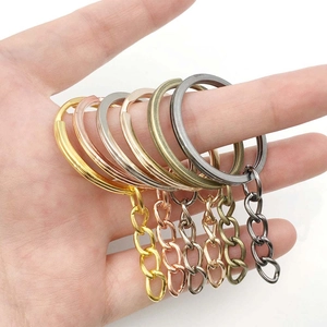 Close-up of five colorful metal split key rings with chains held in a person's hand