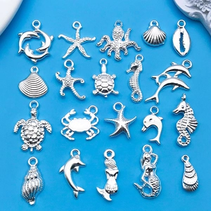 Plano detalle de dijes marinos de aleación plateada como delfines y estrellas para joyas