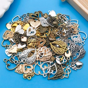 Detailopname van hart- en vleugelbedeltjes in goud zilver en brons voor DIY sieraden