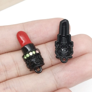 Macro shot of lipstick pendant charm with red oil drip finish and colorful rhinestones