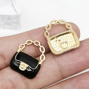 Detail of cartoon handbag charm showing black enamel finish and gold metal chain handle