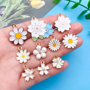 Gros plan de divers pendentifs en émail de marguerites et cerisiers pour comparer la taille