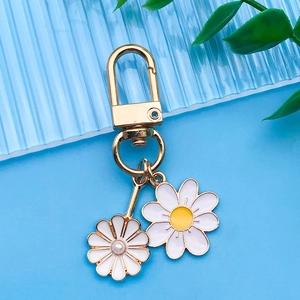 Détail de pendentifs marguerites blancs avec fermoir doré sur fond à rayures bleues
