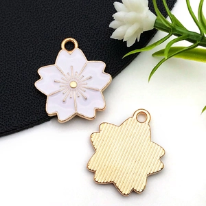 Détail des breloques fleur de cerisier en alliage avec émail blanc et rayures dorées