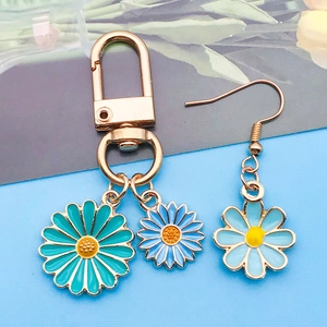 Détail de breloques marguerites en émail bleu pour bijoux avec finition en métal doré