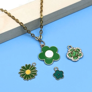 Détail de pendentifs fleurs en émail vert incluant tournesol et rose sur alliage doré
