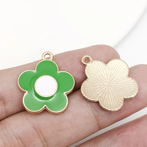 Détail d'un pendentif fleur en émail vert avec dos doré texturé et anneau pour bijoux