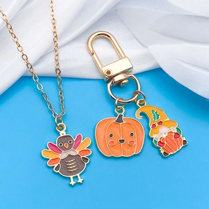 Detalle de colgantes de pavo y calabaza en esmalte colorido con collar y llavero dorados