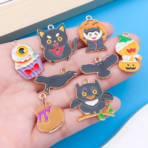 Vista de mano mostrando pequeños colgantes de Halloween esmaltados con fantasmas