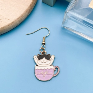 Dettaglio di un orecchino con gatto in tazza di caffè su sfondo azzurro