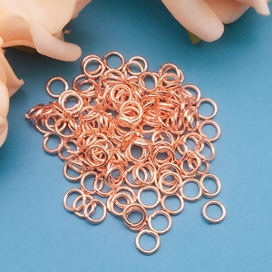 Macro di anellini aperti in oro rosa per gioielli fai da te con sfondo floreale