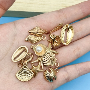 Macro shot of gold ocean themed charms including starfish and shells with pearl inlay
