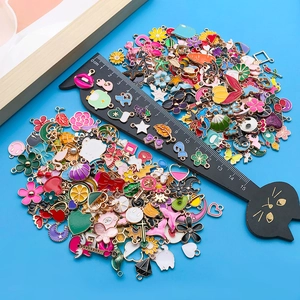Close-up of colorful enamel alloy pendants in various shapes next to a black cat ruler