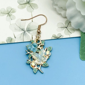 Detail von hellblauer Rose und durchscheinendem Schmetterlingsanhänger mit Strass auf Gold