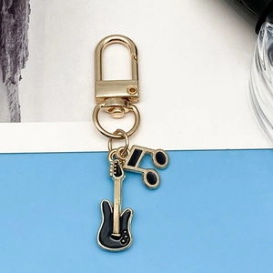 Detailed view of gold lobster clasp with black enamel guitar and musical note pendant