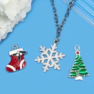 Detalle de dijes navideños con calcetín rojo, copo de nieve blanco y árbol de Navidad