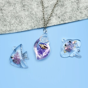 Détail de breloques marines en résine violette avec coquillages et paillettes pour bijoux