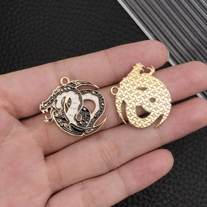 Golden dragon charm with black and white enamel detail and textured back