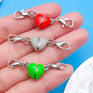 Vista macro delle chiusure magnetiche a cuore smaltato con doppio moschettone per gioielli DIY