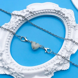Dettaglio del ciondolo a cuore luminoso su catena d'argento con chiusure a moschettone