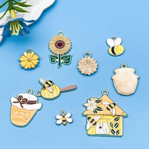 Primer plano de colgantes de abeja de esmalte amarillo y flores para joyería casera