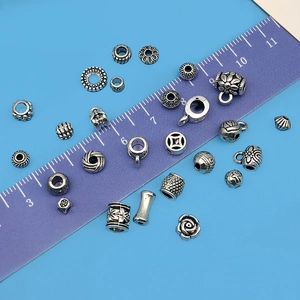 Assorted vintage silver spacer beads and charms for DIY jewelry making with ruler scale