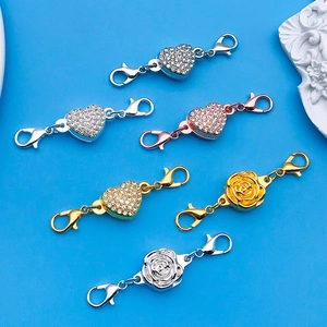 Detail of heart and rose magnetic jewelry clasps with lobster claws on blue background