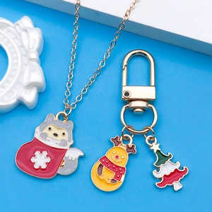 Detalle del collar de lobo navideño en esmalte y llavero de reno con árbol festivo