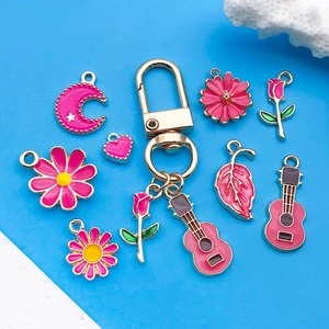 Pink enamel pendants in heart, rose and guitar shapes on a gold lobster clasp keychain