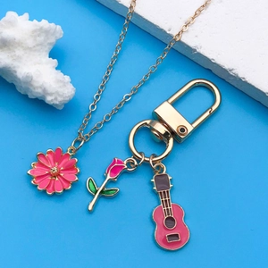 Detail of rose and guitar charms with pink daisy pendant on golden lobster clasp