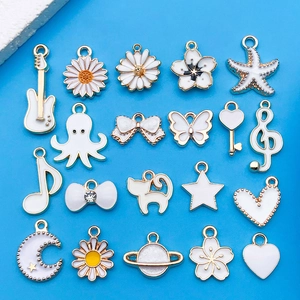 Flat lay of 20 white and gold DIY jewelry charms including music notes and floral shapes