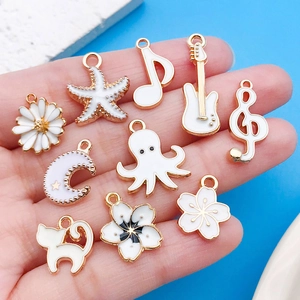 Detail of white enamel alloy charms featuring musical notes and guitar for DIY jewelry
