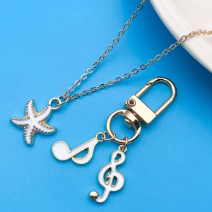 Detail of gold charms including white enamel music notes and starfish for DIY jewelry
