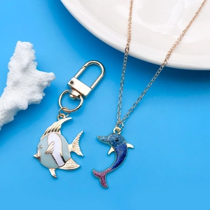 Détail du porte-clés poisson vert et du pendentif dauphin bleu sur un fond bleu brillant