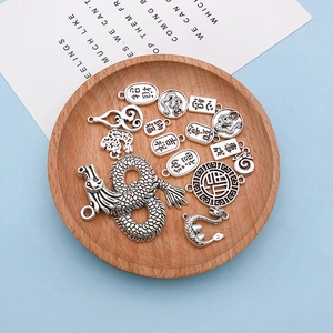 Macro shot of vintage silver dragon pendants and Chinese fortune charms on a wood plate