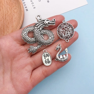 Macro detail of four antique silver alloy charms featuring dragon and Fu characters