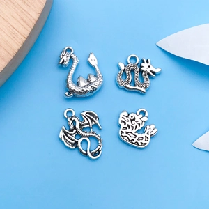 Close-up of four antique silver dragon charms for DIY jewelry making and necklaces
