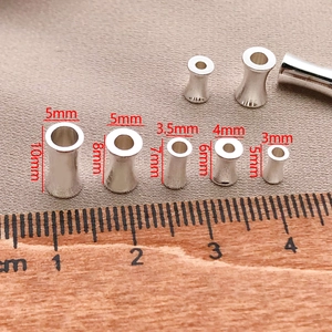 Silberne Sanduhr-Abstandshalter in verschiedenen Größen für DIY-Schmuck auf Holzlineal